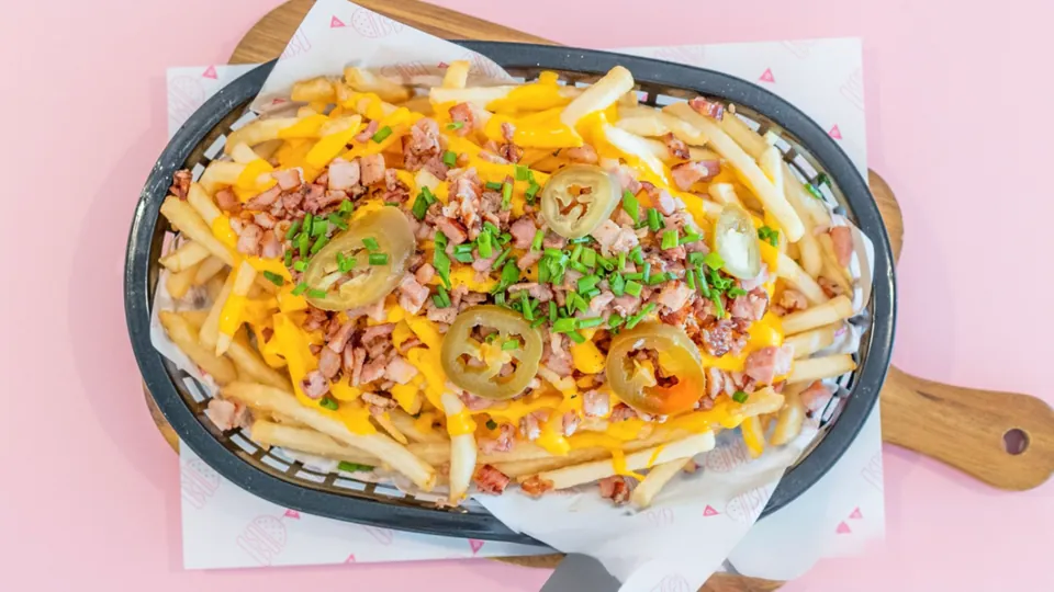 Cheesy Bacon Fries – Thin + crispy fries topped with cheesy sauce, bacon bits, jalapeños + spring onions.